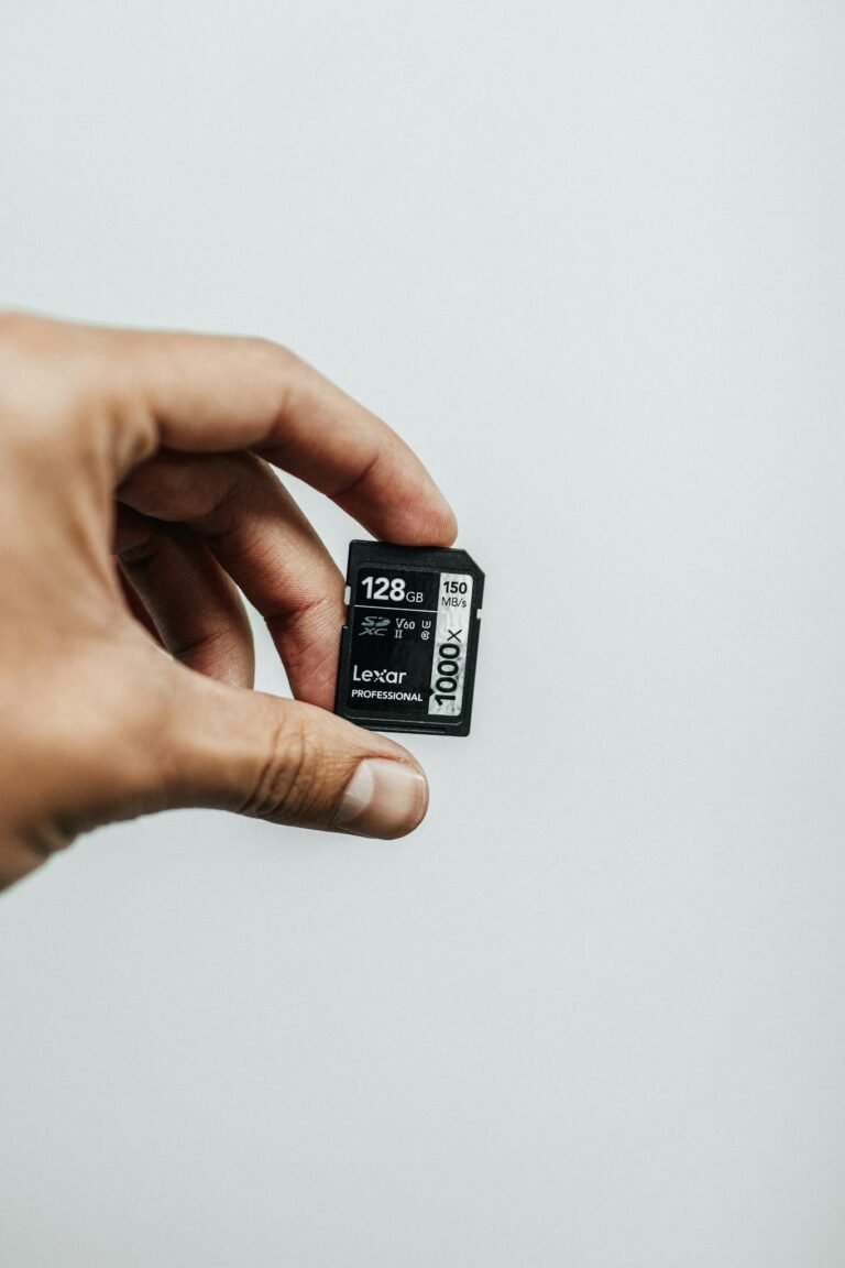 Close-up image of a hand holding a 128GB Lexar Professional SD card against a plain background.